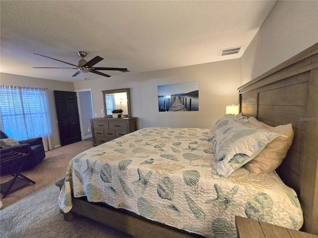 carpeted bedroom featuring ceiling fan and a textured ceiling