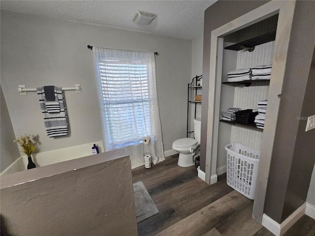 bathroom with hardwood / wood-style floors, a textured ceiling, and toilet