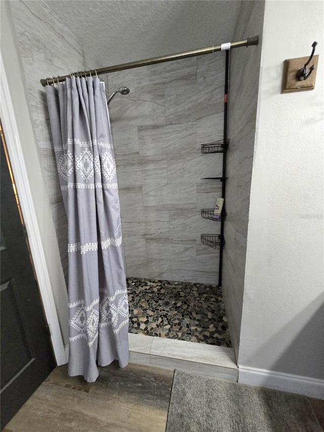 bathroom featuring hardwood / wood-style floors, walk in shower, and a textured ceiling