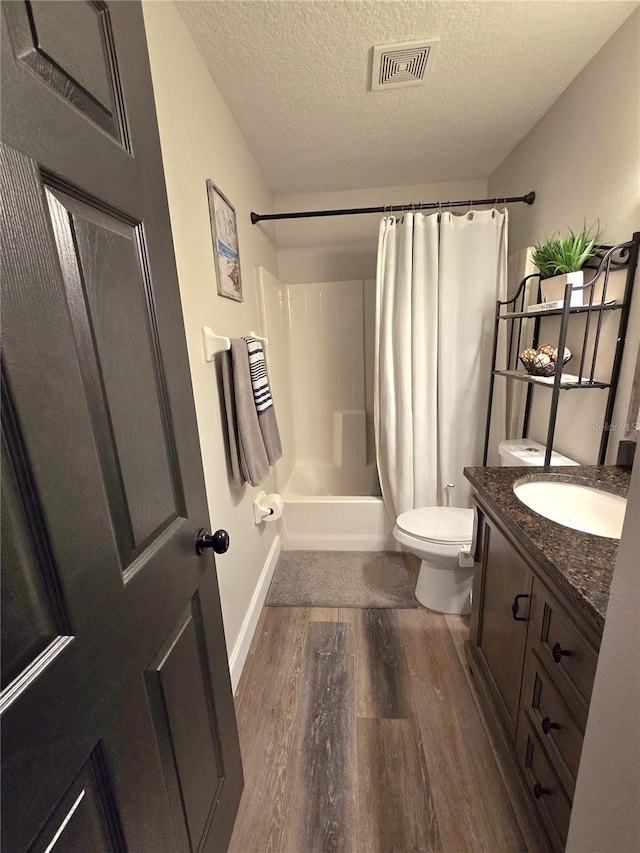 full bathroom featuring hardwood / wood-style floors, a textured ceiling, toilet, shower / bath combo with shower curtain, and vanity