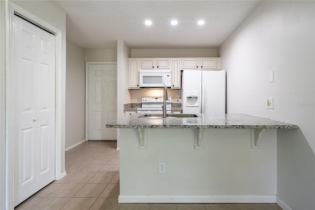 kitchen with a kitchen breakfast bar, white cabinetry, light stone counters, and white appliances