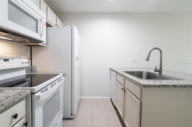 kitchen featuring light tile patterned floors, white appliances, light stone counters, and sink