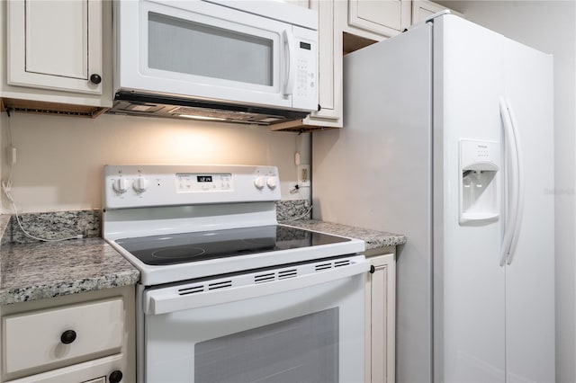 kitchen with white cabinets, light stone counters, and white appliances