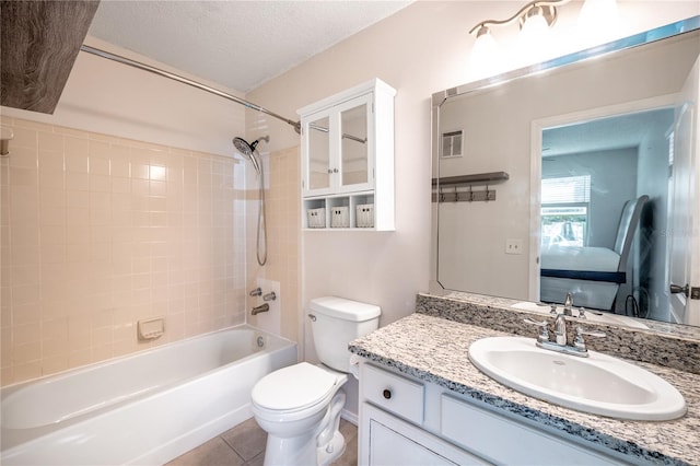 full bathroom with tiled shower / bath combo, tile patterned floors, a textured ceiling, toilet, and vanity