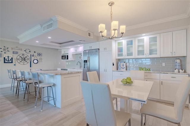 dining space featuring a chandelier, light wood-type flooring, ornamental molding, and sink