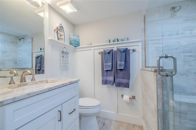 bathroom with wood-type flooring, vanity, a shower with shower door, and toilet