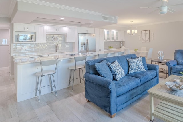 living room with crown molding, light hardwood / wood-style flooring, and ceiling fan with notable chandelier