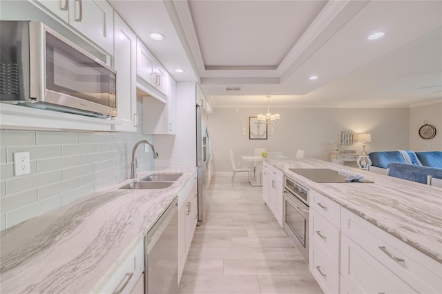 kitchen with light stone countertops, sink, stainless steel appliances, tasteful backsplash, and white cabinets