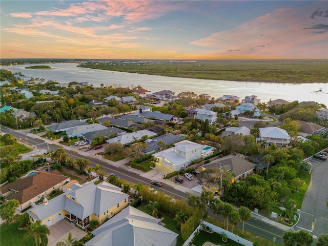 aerial view at dusk featuring a water view