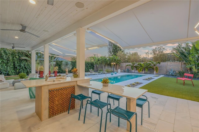 view of patio featuring a bar, a fenced in pool, and ceiling fan