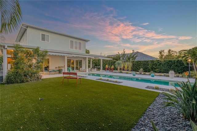 pool at dusk featuring a patio area and a yard