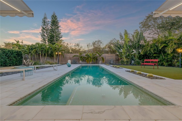 pool at dusk with a lawn and a patio area