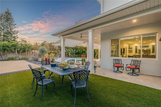 patio terrace at dusk featuring a yard