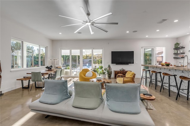 living room with an inviting chandelier, sink, and concrete floors