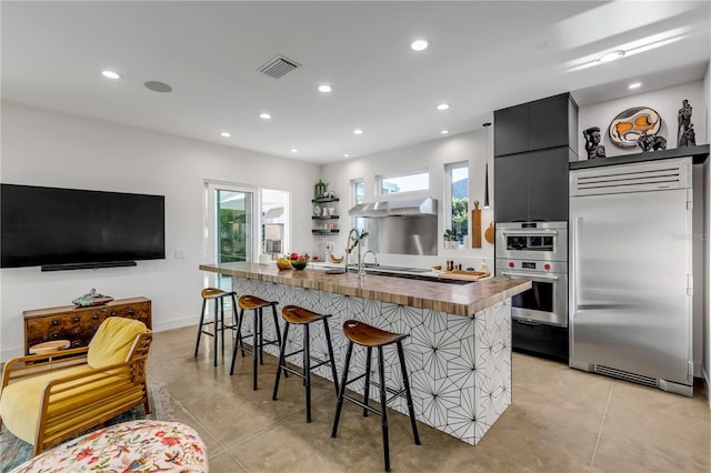 kitchen featuring a kitchen breakfast bar, a wealth of natural light, ventilation hood, and appliances with stainless steel finishes