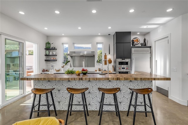 kitchen featuring sink, a center island with sink, butcher block counters, and a breakfast bar area