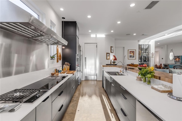 kitchen with sink, hanging light fixtures, wall chimney range hood, and stainless steel gas cooktop