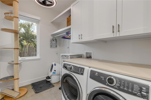 clothes washing area with cabinets and separate washer and dryer