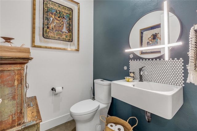 bathroom featuring tasteful backsplash, toilet, and sink