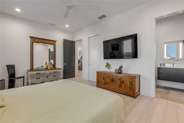 bedroom featuring ensuite bathroom, ceiling fan, and light wood-type flooring