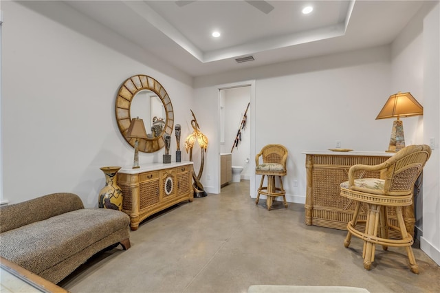 living area featuring a raised ceiling and concrete floors