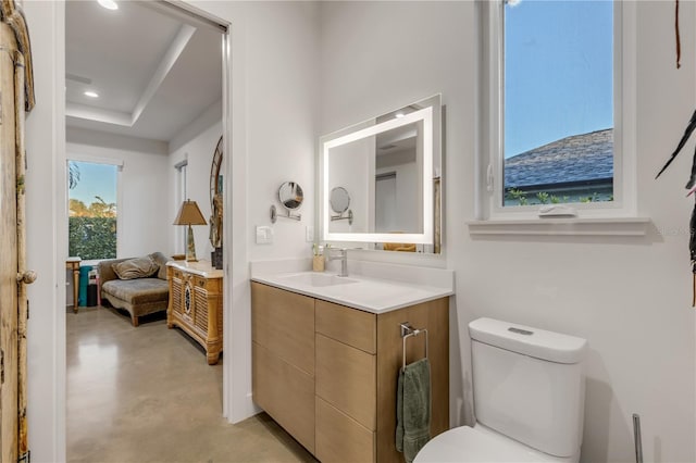 bathroom featuring vanity, concrete floors, a tray ceiling, and toilet