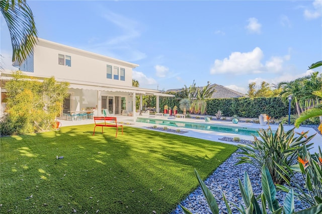 back of property with a fenced in pool, a yard, and a patio