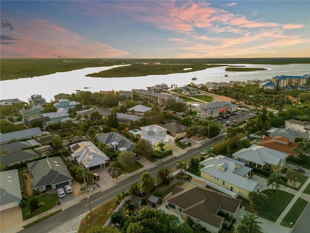 aerial view at dusk featuring a water view