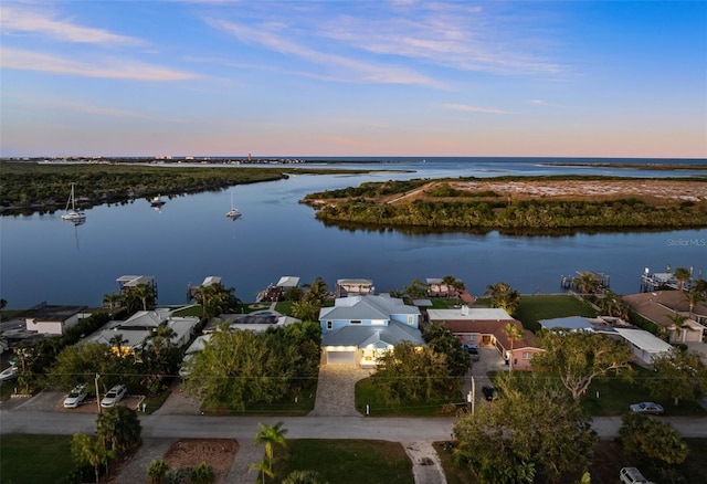 aerial view at dusk featuring a water view