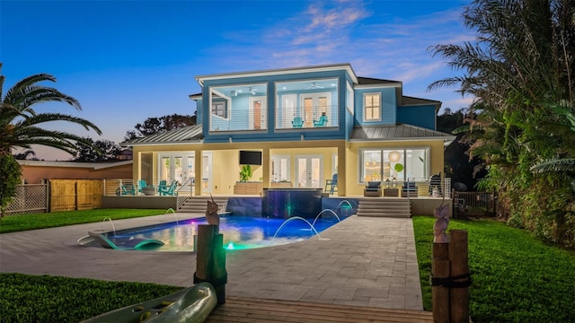 back of property featuring french doors, pool water feature, a fenced in pool, and a patio