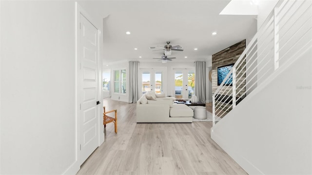 entryway with french doors, light wood-type flooring, a skylight, ceiling fan, and crown molding