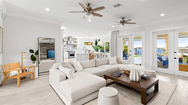 living room featuring crown molding, french doors, ceiling fan, and light hardwood / wood-style flooring