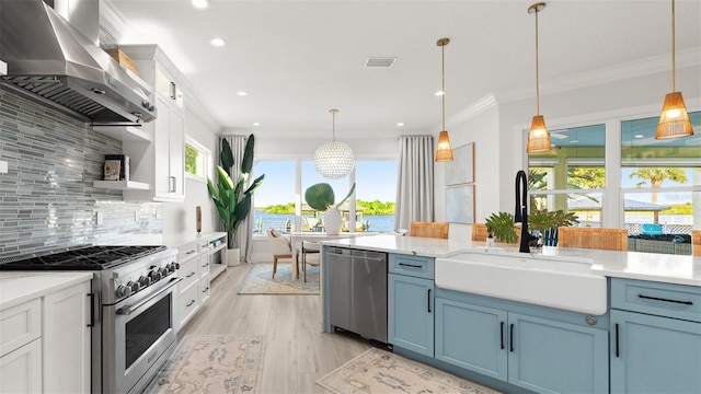 kitchen featuring wall chimney exhaust hood, sink, hanging light fixtures, and appliances with stainless steel finishes