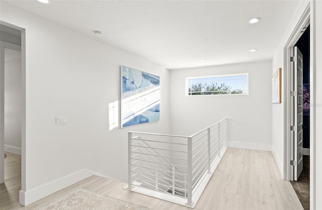 hall with light hardwood / wood-style floors and a textured ceiling