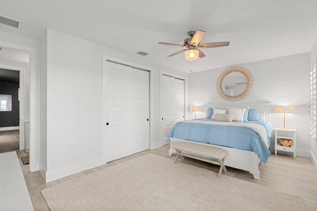 bedroom with ceiling fan, two closets, and light wood-type flooring