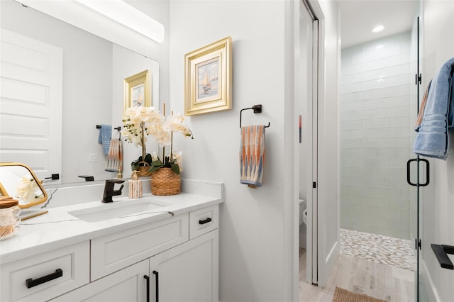 bathroom with walk in shower, hardwood / wood-style flooring, vanity, and toilet