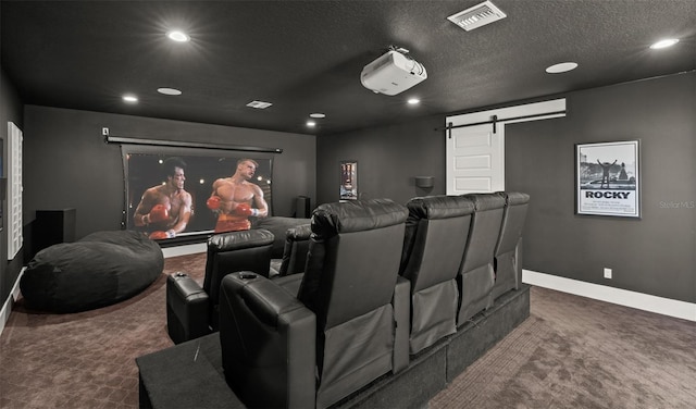 carpeted home theater featuring a barn door and a textured ceiling