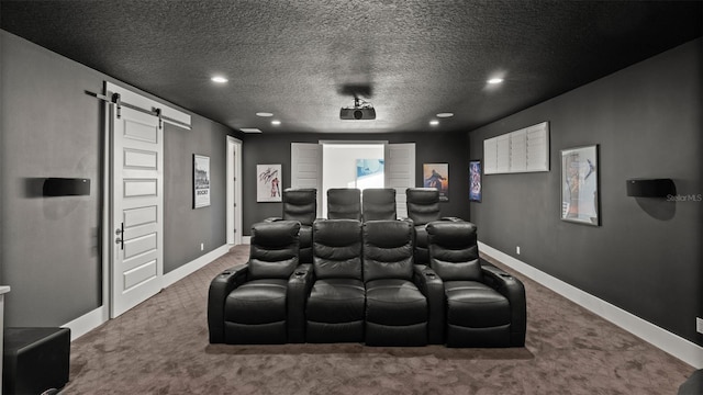 carpeted home theater room with a barn door and a textured ceiling