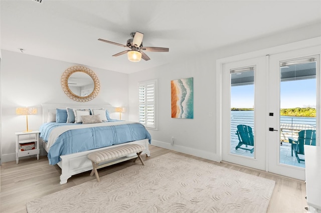 bedroom with french doors, access to outside, ceiling fan, a water view, and light hardwood / wood-style floors