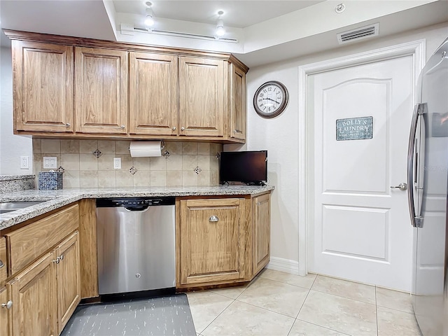 kitchen with dishwasher, tasteful backsplash, light stone counters, a tray ceiling, and light tile patterned floors