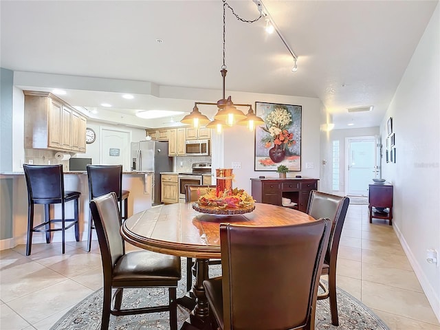 dining space with light tile patterned flooring and rail lighting