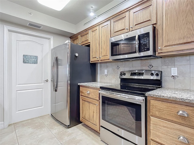 kitchen with tasteful backsplash, light stone counters, light tile patterned flooring, and stainless steel appliances