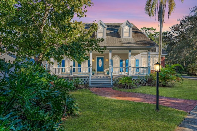 cape cod house with a porch and a yard