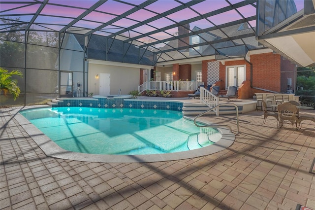 pool at dusk with french doors, a patio, and a lanai