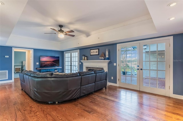 living room featuring french doors, ornamental molding, a tray ceiling, ceiling fan, and hardwood / wood-style flooring