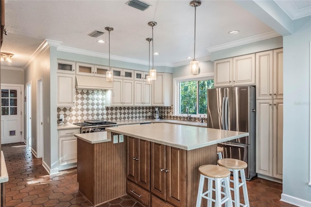 kitchen with stainless steel appliances, decorative light fixtures, decorative backsplash, a kitchen island, and ornamental molding