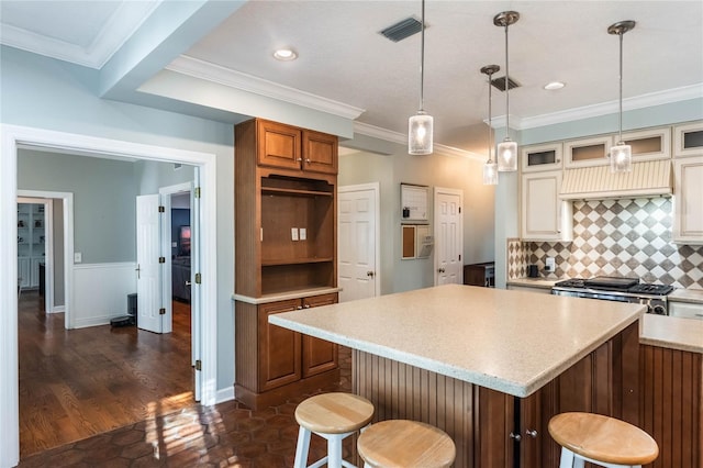 kitchen featuring decorative backsplash, dark hardwood / wood-style flooring, a breakfast bar, crown molding, and a kitchen island