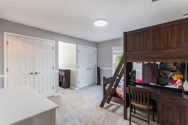 carpeted bedroom featuring multiple closets and a textured ceiling