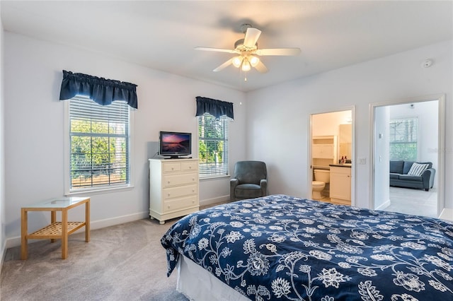 bedroom with multiple windows, light carpet, ensuite bathroom, and ceiling fan