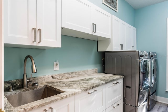 clothes washing area with separate washer and dryer, sink, cabinets, and wood-type flooring